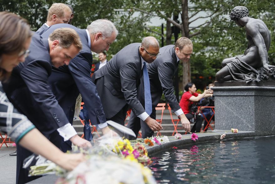 Mourners place flowers at the fountain edge before a vigil in Fountain Square where a shooting took place the previous day that claimed the lives of three civilians, Friday, Sept. 7, 2018, in Cincinnati. Suspect Omar Enrique Santa Perez entered the Fifth Third Center and began firing before being neutralized by police officers. (AP Photo/John Minchillo)
