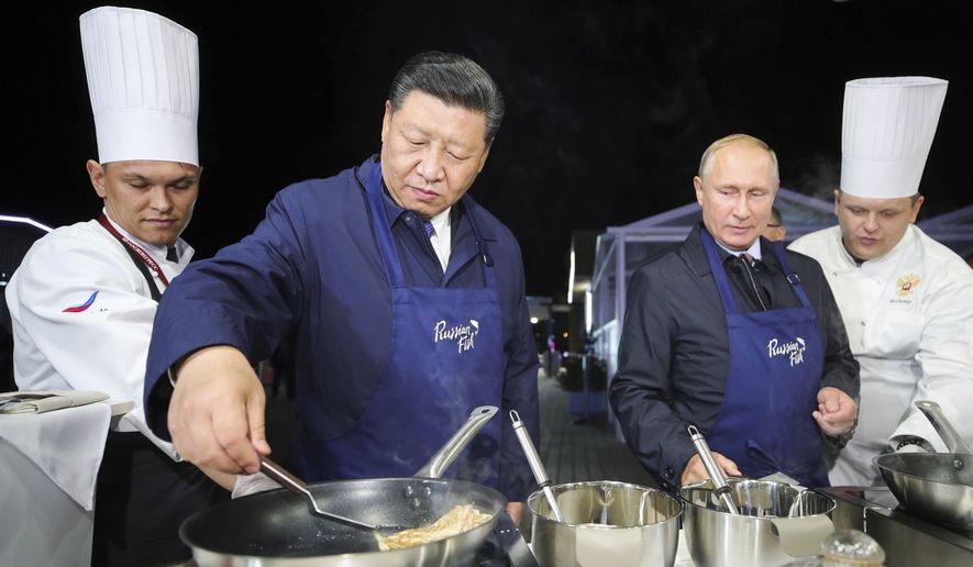 Chinese President Xi Jinping, second left, and Russian President Vladimir Putin, second right, prepare food, as they visit an exhibition during the Eastern Economic Forum in Vladivostok, Russia, Tuesday, Sept. 11, 2018. (Sergei Bobylev/TASS News Agency Pool Photo via AP)