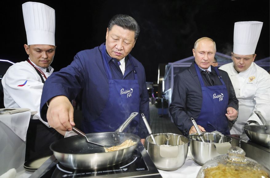 Chinese President Xi Jinping, second left, and Russian President Vladimir Putin, second right, prepare food, as they visit an exhibition during the Eastern Economic Forum in Vladivostok, Russia, Tuesday, Sept. 11, 2018. (Sergei Bobylev/TASS News Agency Pool Photo via AP)