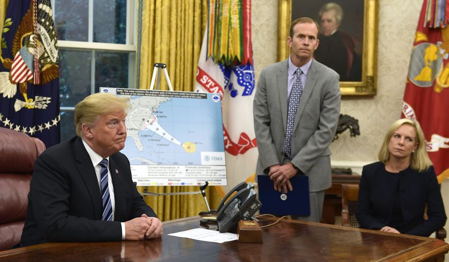 President Donald Trump, left, listens to a reporters question as FEMA Administrator Brock Long, center, and Homeland Security Secretary Kirstjen Nielsen, right, listen during a briefing on Hurricane Florence in the Oval Office of the White House in Washington, Tuesday, Sept. 11, 2018. (AP Photo/Susan Walsh)