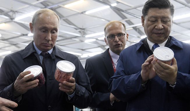Chinese President Xi Jinping, right, and Russian President Vladimir Putin look at containers of food as they visit an exhibition during the Eastern Economic Forum in Vladivostok, Russia, Tuesday, Sept. 11, 2018. (Kirill Kudryavtsev Photo via AP)