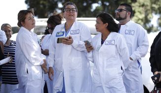 Hospital staff wait outside after they were evacuated from Kaiser Permanente Downey Medical Center, following reports of someone with a weapon at the facility in Downey, Calif., Tuesday, Sept. 11, 2018. Los Angeles County sheriff&#39;s officials say a suspect is in custody and deputies and police officers are methodically searching the complex. (AP Photo/Jae C. Hong)