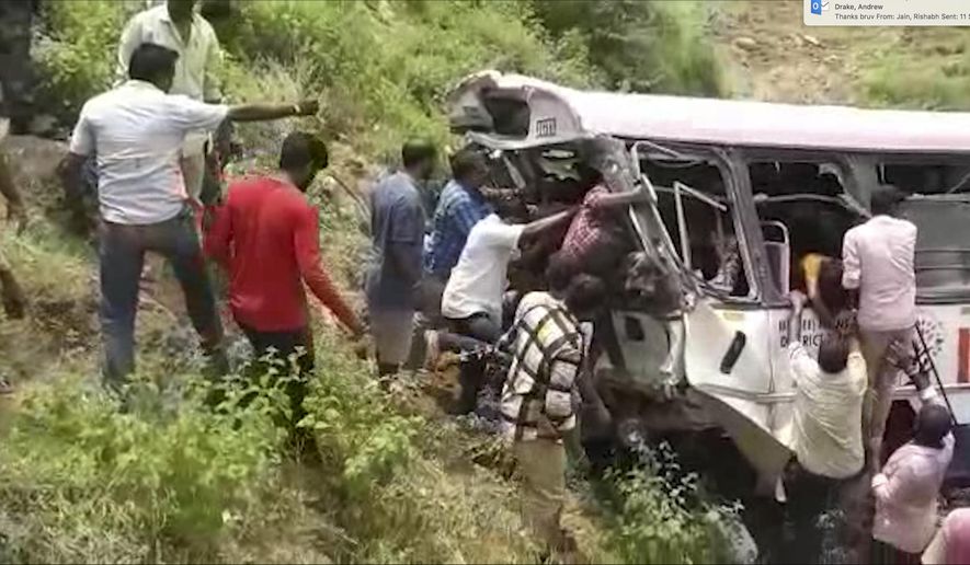 In this grab made from video provided by KK Productions, rescuers pull out passengers from a bus that fell into a gorge in Jagtiyal district of Telangana, India, Tuesday, Sept. 11, 2018. The bus was carrying pilgrims from a Hindu temple in the hills of south India when it plunged off a road  killing several people (KK Production via AP)