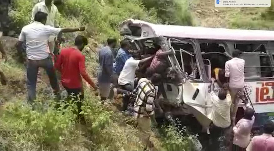 In this grab made from video provided by KK Productions, rescuers pull out passengers from a bus that fell into a gorge in Jagtiyal district of Telangana, India, Tuesday, Sept. 11, 2018. The bus was carrying pilgrims from a Hindu temple in the hills of south India when it plunged off a road  killing several people (KK Production via AP)
