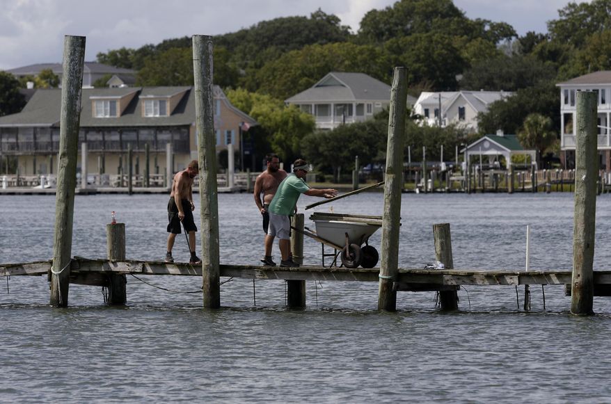 From left, Josh Clappsy, Blake Price, and JB Phillips remove boards from a dock in hopes to save it from rising waters in Swansboro, N.C., Tuesday, Sept. 11, 2018. Florence exploded into a potentially catastrophic hurricane Monday as it closed in on North and South Carolina, carrying winds up to 140 mph (220 kph) and water that could wreak havoc over a wide stretch of the eastern United States later this week. (AP Photo/Tom Copeland)