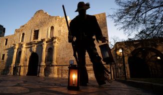 Dan Phillips, a member of the San Antonio Living History Association, collects lanterns following a pre-dawn memorial ceremony to remember the 1836 Battle of the Alamo and those who fell on both sides, Wednesday, March 6, 2013, in San Antonio. (AP Photo/Eric Gay)
