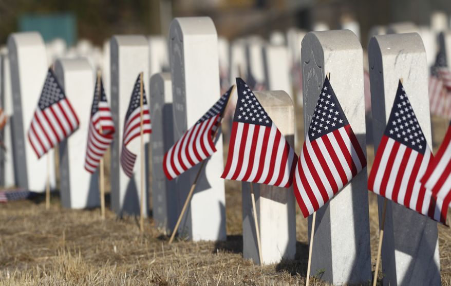 American flags stand next to the markers amid the headstones of veterans and their family members to mark Veterans Day in Riverside Cemetery on Friday, Nov. 11, 2016, in Denver. (AP Photo/David Zalubowski)