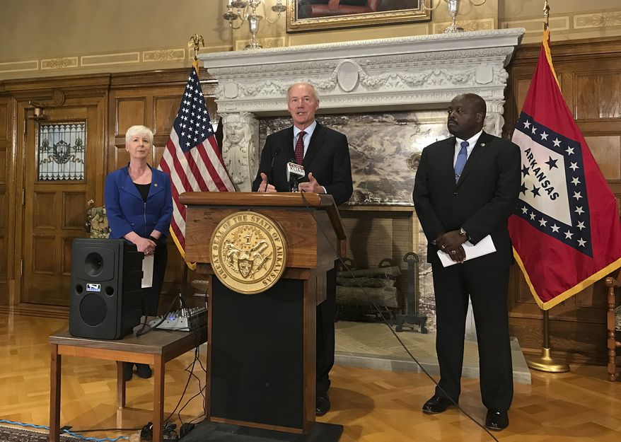 Arkansas Gov. Asa Hutchinson, center, talks at a news conference at the State Capitol in Little Rock, Ark., Wednesday, September 12, 2018, about the state's work requirement for its expanded Medicaid program. Officials said more than 4,300 people on the program lost coverage for not meeting the new work requirement. (AP Photo/Andrew DeMillo)