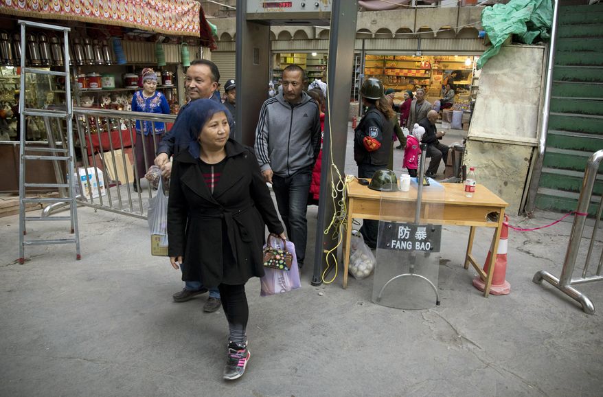 FILE - In this Nov. 4, 2017 photo, residents past through one of the many security check points in Kashgar in western China's Xinjiang region. Two U.S. lawmakers are urging the extension of American export restrictions to prevent sales of equipment that could be used in China’s massive security clampdown targeting the Xinjiang region’s native Muslim population. Sen. Marco Rubio and Rep. Chris Smith said in a letter, Wednesday, Sept. 12, 2018, to the U.S. commerce secretary that they want foreign entities, including businesses, research institutions, government and private organizations, and individuals seen as profiting from the clampdown added to a watch list. (AP Photo/Ng Han Guan, File)