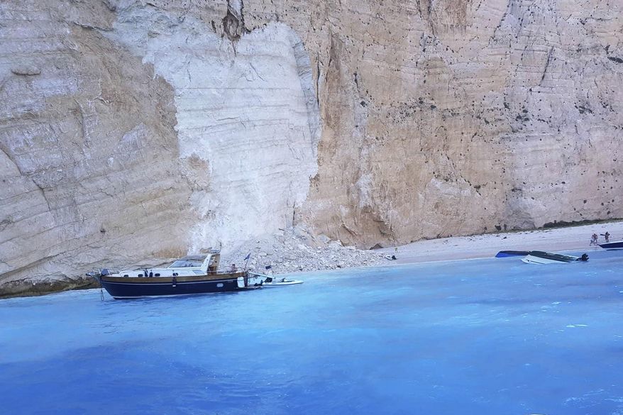 Small boats are capsized after a landslide occurred at the popular beach of Navagio, or Shipwreck Beach, on the western island of Zakynthos, Greece, Thursday, Sept. 13, 2018. Greek authorities say a landslide at a popular beach on the western island of Zakynthos has resulted in at least one injury, while coast guard officials were seeking to determine whether there were any people missing. (imerazante.gr via AP)