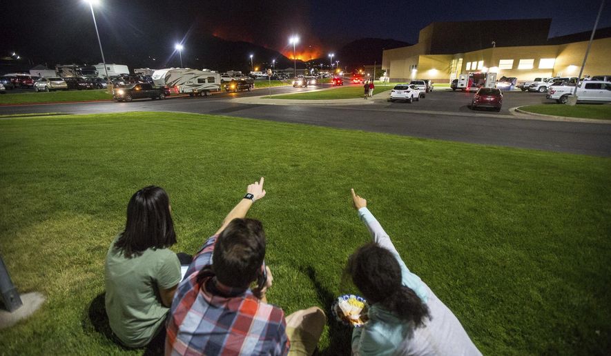 In this Thursday, Sept. 13, 2018, photo, residents watch a wildfire burning from outside Salem Hills High School in Salem, Utah. (Qiling Wang/The Deseret News via AP)