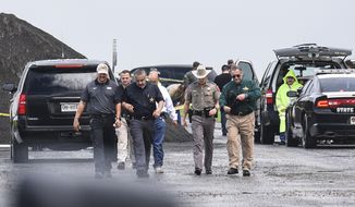 Law enforcement officers gather near the scene where the body of a woman was found near Interstate 35 north of Laredo, Texas on Saturday, Sept. 15, 2018. A U.S. Border Patrol agent suspected of killing four women was arrested early Saturday after a fifth woman who had been abducted managed to escape from him and notify authorities, law enforcement officials said, describing the agent as a &amp;quot;serial killer.&amp;quot; (Danny Zaragoza/The Laredo Morning Times via AP)
