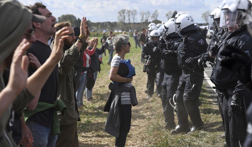 Protesters are observed by the Police as they try to enter the Hambach forest in Kerpen, Germany, Saturday, Sept. 15, 2018. German energy company RWE plans clearing and grubbing the forest for their open-pit lignite mine nearby to continue digging for brown coal. (Henning Kaiser/dpa via AP)