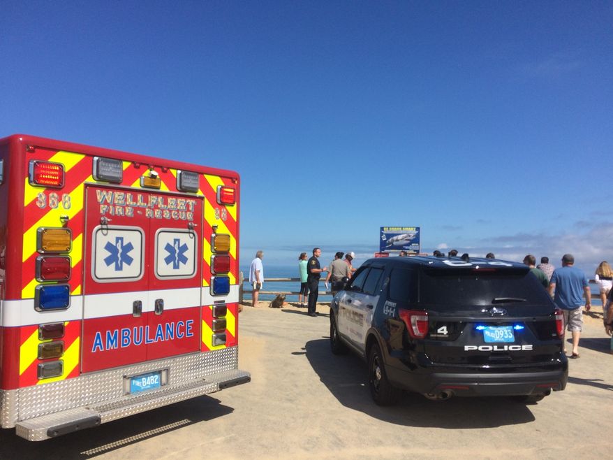 Emergency personnel respond to Newcomb Hollow Beach in Wellfleet, Mass, on Saturday, Sept. 15, 2018. The Cape Cod Times says rescue crews responded to Newcomb Hollow Beach in Wellfleet at around noon Saturday after one person was apparently bitten by a shark. It’s not immediately clear the extent of the person’s injuries. (Eric Williams/The Cape Cod Times via AP)