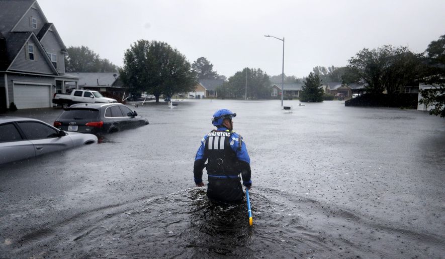A member of the North Carolina Task Force urban search and rescue team wades through a flooded neighborhood looking for residents who stayed behind as Florence continues to dump heavy rain in Fayetteville, N.C., Sunday, Sept. 16, 2018. (AP Photo/David Goldman)