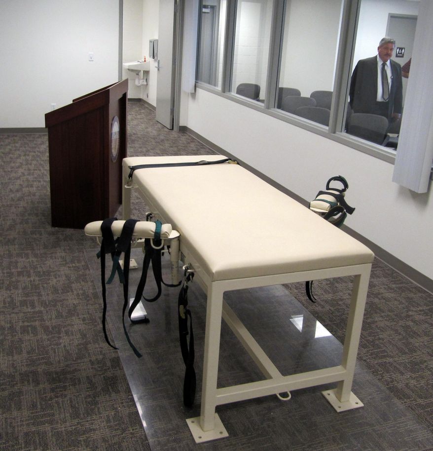 FILE - This Oct. 20, 2011 file photo shows the execution chamber at the Idaho Maximum Security Institution as Warden Randy Blades, right, stands in the observation room, in Boise, Idaho. An Idaho judge now says state prison officials can hold off on identifying where they obtain the drugs used in executions until a trial is held on the matter. (AP Photo/Jessie L. Bonner, File)