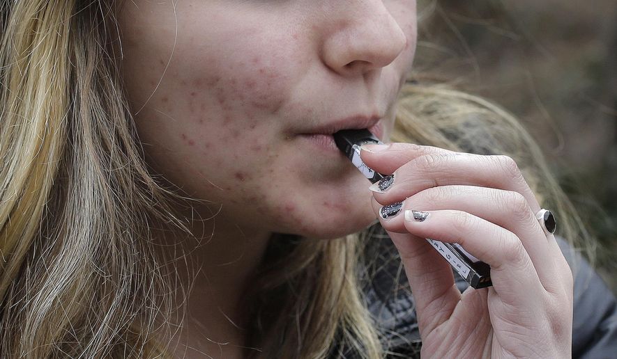 In this April 11, 2018, file photo, an unidentified 15-year-old high school student uses a vaping device near the school&#39;s campus in Cambridge, Mass. (AP Photo/Steven Senne, File)