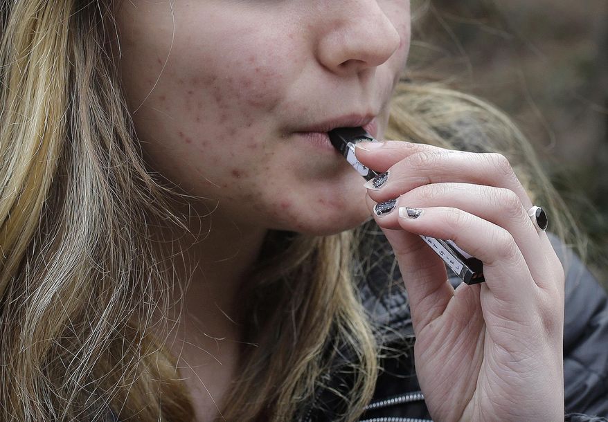 In this April 11, 2018, file photo, an unidentified 15-year-old high school student uses a vaping device near the school's campus in Cambridge, Mass. (AP Photo/Steven Senne, File)