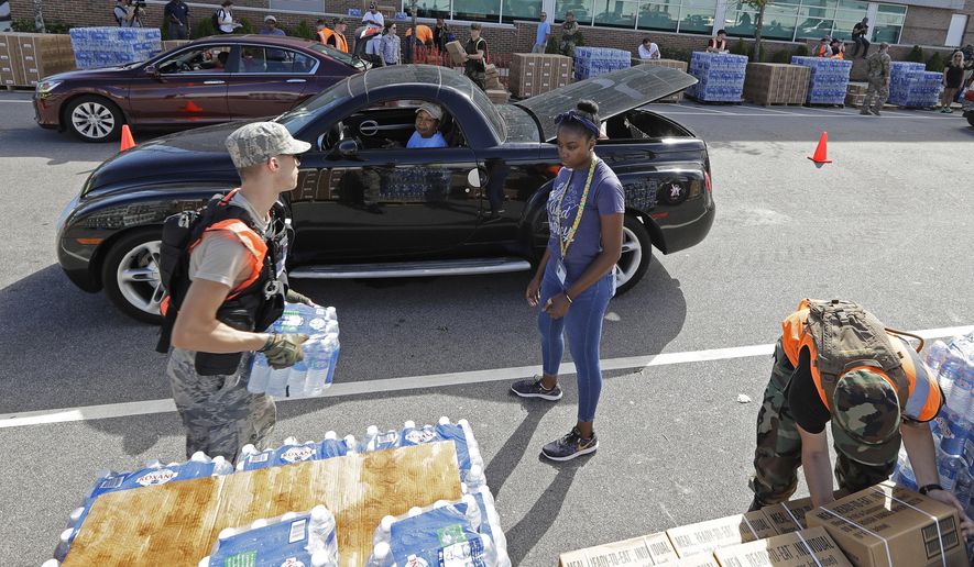 Members of the Civil Air Patrol load cars with MREs, (Meals Ready To Eat) water and tarps at distribution area in Wilmington, N.C. Tuesday, Sept. 18, 2018. (AP Photo/Chuck Burton)
