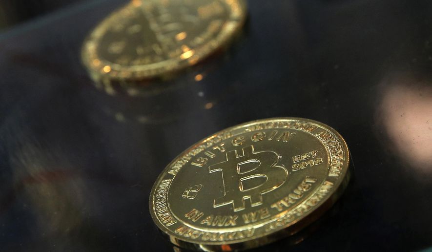 In this Dec. 8, 2017, file photo, coins are displayed next to a bitcoin ATM in Hong Kong. (AP Photo/Kin Cheung, File)