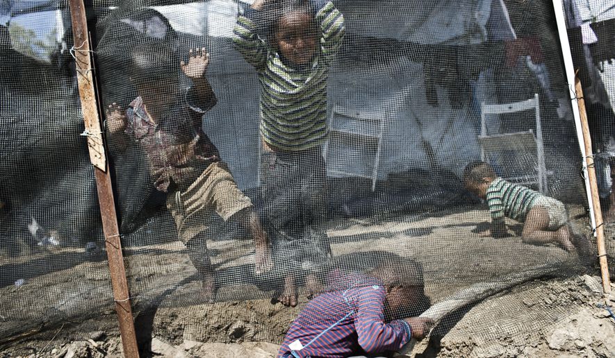 FILE - In this Wednesday, May, 2, 2018, file photo, children play inside the Moria refugee camp on the northeastern Aegean island of Lesbos, Greece.  The jammed Moria camp on the Greek island of Lesbos and the dangerous migrant detention centers in Libya serve as a sober reminder to European leaders that their statistical success in curbing migration into the continent has spawned what the U.N. and others condemn as massive humanitarian failures. Deeply divided over how and where to control Europe’s borders, leaders are meeting Wednesday, Sept. 19, 2018 in a summit in Austria. (AP Photo/Petros Giannakouris, File)