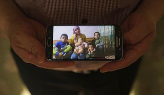 In this Aug. 23, 2018, photo, Adil, 42, father to five children and a businessman from Kashgar, China, holds a phone showing an image of his family left behind in China while being interviewed by the Associated Press in Istanbul, Turkey. He got stuck in Turkey during a business trip after hearing that the Chinese government was seizing passports, and hasn&#39;t seen his children since. Three of his children were ordered to attend newly-built boarding schools in Kashgar and Turpan before he got stuck in Turkey. (AP Photo/Dake Kang)