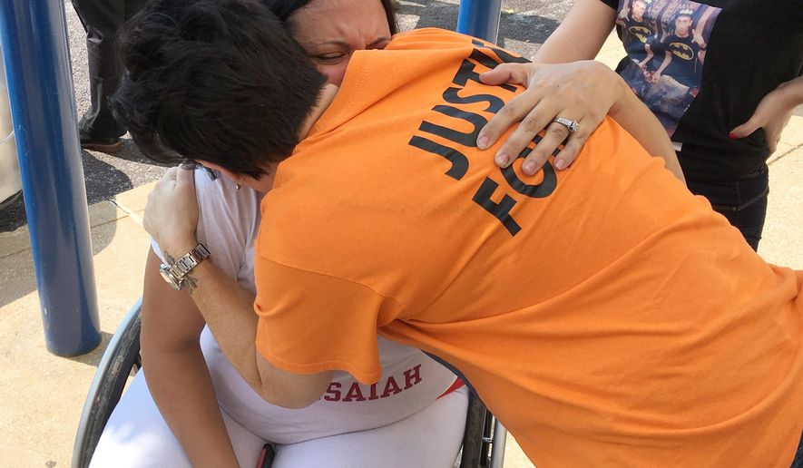Gina Torres, seated, gets a hug from Bridgette Perkins during a rally in St. Louis Thursday, Sept. 20, 2018, demanding that a police internal investigations unit complete its probe into the fatal police shooting of Torres' son, Isaiah Hammett. Hammett was killed in a SWAT raid at his home in June 2017. Perkins' son, Isiah Perkins, also was killed by a St. Louis officer, in July 2017. (AP Photo/Jim Salter)