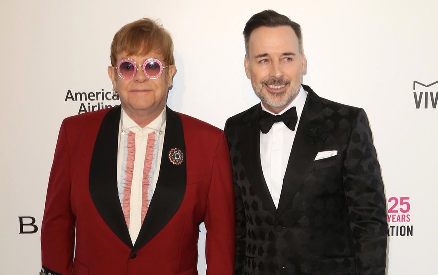 FILE - In this Sunday, March 4, 2018 file photo,  Elton John, left, and David Furnish arrive at the 2018 Elton John AIDS Foundation Oscar Viewing Party, in West Hollywood, Calif. Singer Elton John and partner David Furnish have accepted an apology and undisclosed libel damages over a newspaper report that their dog severely injured a child while on a play date.  (Photo by Willy Sanjuan/Invision/AP, File)