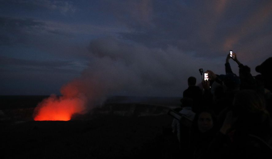 FILE - In this May, 9, 2018, file photo, visitors take pictures as Kilauea&#x27;s summit crater glows red in Volcanoes National Park, Hawaii. The Hawaii Volcanoes National Park will reopen its main gates Saturday, Sept. 22, 2018, welcoming carloads of visitors eager to see Kilauea&#x27;s new summit crater and the area where a longstanding lava lake once bubbled near the surface. The park has been closed for 135 days as volcanic activity caused explosive eruptions, earthquakes and the collapse of the famed Halemaumau crater. (AP Photo/Jae C. Hong, File)
