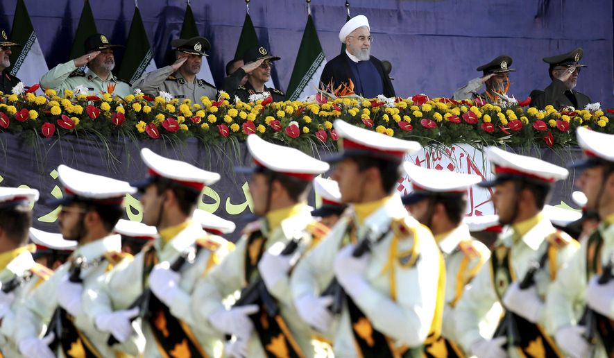 Iran&#39;s President Hassan Rouhani, top center, reviews army troops marching during the 38th anniversary of Iraq&#39;s 1980 invasion of Iran, in front of the shrine of the late revolutionary founder, Ayatollah Khomeini, outside Tehran, Iran, Saturday, Sept. 22, 2018. Gunmen attacked the military parade, killing at least eight members of the elite Revolutionary Guard and wounding 20 others, state media said. (AP Photo/Ebrahim Noroozi)