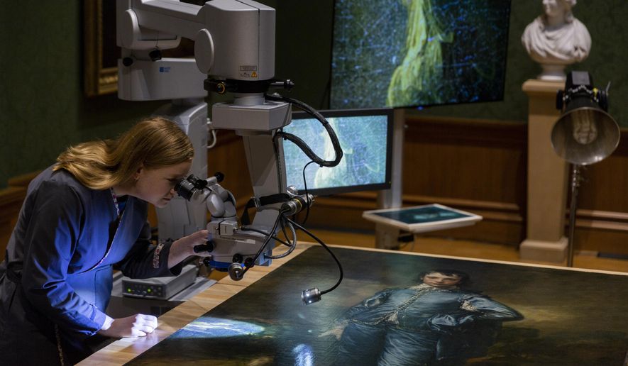 In this Thursday, Sept. 20, 2018, photo The Huntington's senior paintings conservator, Christina O'Connell, examines "The Blue Boy" painting, made around 1770 by the English painter Thomas Gainsborough (1727-1788), through a Haag-Streit surgical microscope at "Project Blue Boy" exhibit in the Thornton Portrait Gallery at The Huntington in San Marino, Calif. Beginning Saturday, Sept. 22, visitors to The Huntington Library, Art Collections and Botanical Gardens can see conservator Christina O’Connell repair Thomas Gainsborough’s priceless portrait of a boy dressed all in blue. (AP Photo/Damian Dovarganes)