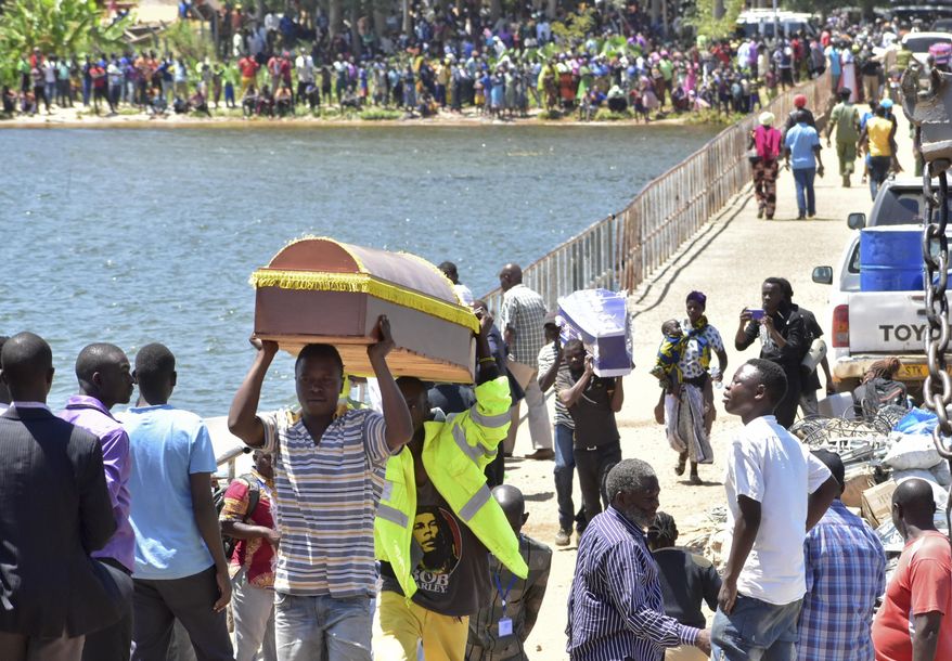 Relatives carry coffins to be used for the victims of the MV Nyerere passenger ferry on Ukara Island, Tanzania Saturday, Sept. 22, 2018. The death toll soared past 200 on Saturday while officials said a survivor was found inside the capsized ferry and search efforts were ending to focus on identifying bodies, two days after the Lake Victoria disaster. (AP Photo/Andrew Kasuku)