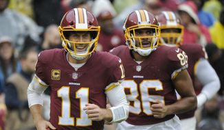 Washington Redskins quarterback Alex Smith (11) smiles as he runs off the filed after wide receiver Jamison Crowder (80) scored a touchdown during the first half of an NFL football game between the Washington Redskins and the Green Bay Packers, Sunday, Sept. 23, 2018 in Landover, Md. (AP Photo/Mark Tenally)