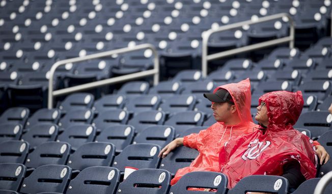 Fans sit in the rain before a baseball game between the Washington Nationals and the New York Mets at Nationals Park, Sunday, Sept. 23, 2018, in Washington. (AP Photo/Andrew Harnik) **FILE**