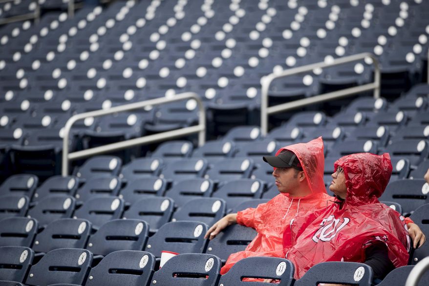 Fans sit in the rain before a baseball game between the Washington Nationals and the New York Mets at Nationals Park, Sunday, Sept. 23, 2018, in Washington. (AP Photo/Andrew Harnik) **FILE**