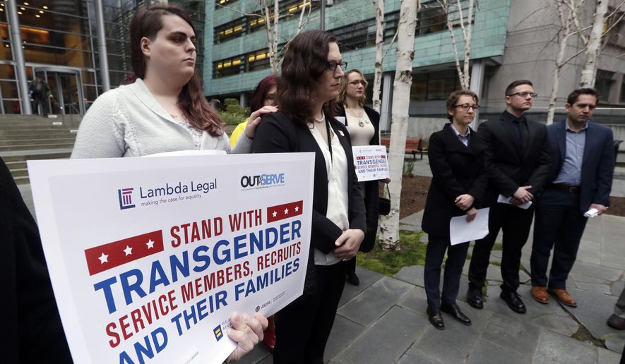 In this March 27, 2018, photo, plaintiffs Cathrine Schmid, second left, and Conner Callahan, second right, listen with supporters during a news conference in front of a federal courthouse following a hearing in Seattle. Transgender-rights activists are angered at moves by President Donald Trump and his administration to undermine gains achieved before his election. Trump is seeking to ban transgender people from military service, although that effort has stalled in court. (AP Photo/Elaine Thompson) **FILE**