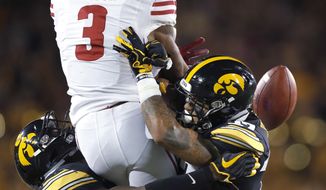Iowa defensive backs Matt Hankins, left, and Amani Hooker, right, dislodge the ball from Wisconsin wide receiver Kendric Pryor, center, resulting in an incomplete pass during the first half of an NCAA college football game Saturday, Sept. 22, 2018, in Iowa City. (AP Photo/Matthew Putney)