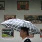 A man carrying an umbrella walks past a display board showing photos of North Korean leader Kim Jong Un&#39;s recent trip to China outside of the North Korean embassy in Beijing, Saturday, April 21, 2018. China, North Korea&#39;s main ally, is welcoming Pyongyang&#39;s decision to suspend its nuclear and missile tests. (AP Photo/Mark Schiefelbein)
