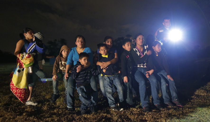 This June 25, 2014, file photo, shows a group of immigrants from Honduras and El Salvador who crossed the U.S.-Mexico border illegally as they are stopped in Granjeno, Texas. (AP Photo/Eric Gay, File)