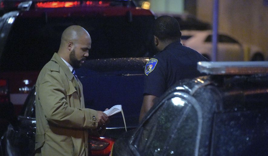 A detective talks with a member of the Baltimore Police outside University of Maryland Shock Trauma, following a shooting in Baltimore on Sunday, Sept. 23, 2018. The shootout between a man in a violence-prone Baltimore district and a police officer taking part in a crime suppression initiative has left the officer wounded and the suspect dead Sunday evening, Baltimore's interim police chief said. (Karl Merton Ferron/The Baltimore Sun via AP)