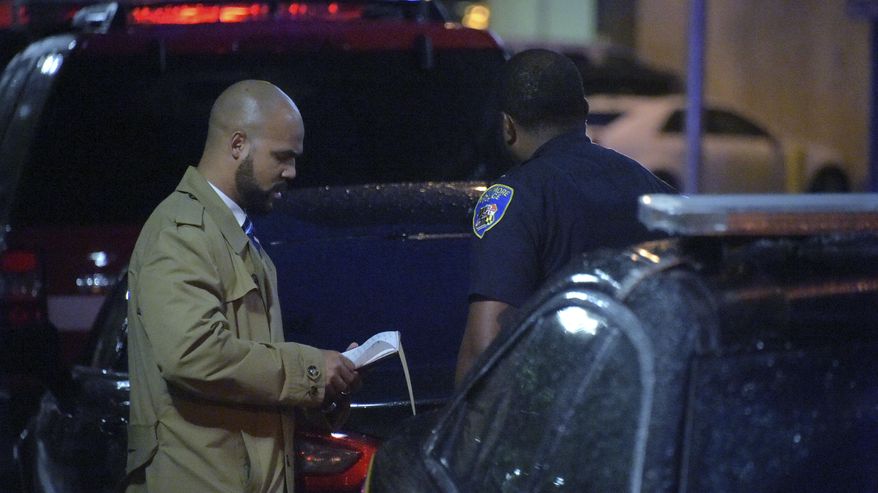 A detective talks with a member of the Baltimore Police outside University of Maryland Shock Trauma, following a shooting in Baltimore on Sunday, Sept. 23, 2018. The shootout between a man in a violence-prone Baltimore district and a police officer taking part in a crime suppression initiative has left the officer wounded and the suspect dead Sunday evening, Baltimore's interim police chief said. (Karl Merton Ferron/The Baltimore Sun via AP)