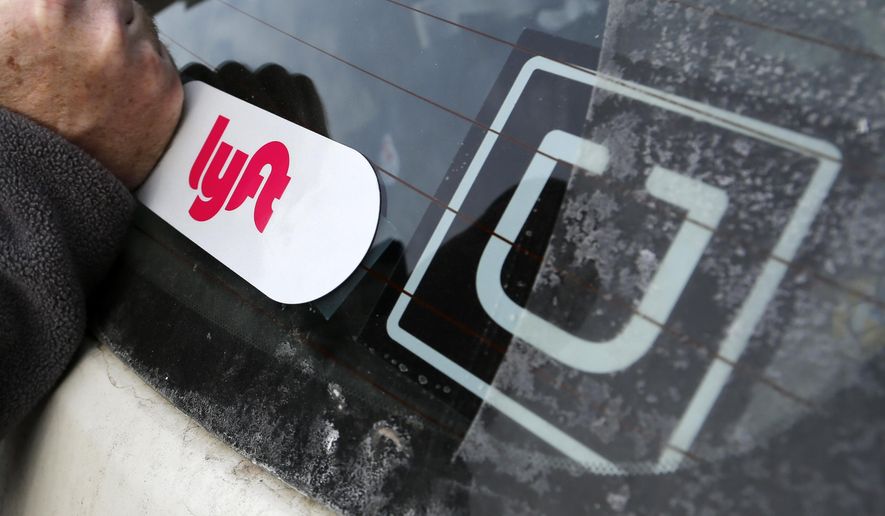 In this Jan. 31, 2018, photo, a Lyft logo is installed on a Lyft driver&#39;s car next to an Uber sticker in Pittsburgh. (AP Photo/Gene J. Puskar) **FILE**