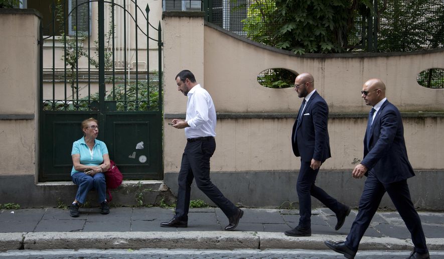Interior Minister Matteo Salvini, second from left, is followed by security guards as he checks his phone while walking in downtown Rome after leaving Palazzo Chigi government office, Monday, Sept. 24, 2018. Salvini, who’s cracking down on migrants, told reporters that the government at a Cabinet meeting Monday approved a decree setting tighter criteria for such protection, a status less than full asylum. (AP Photo/Alessandra Tarantino)