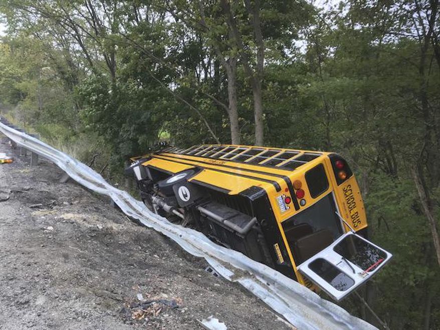 A Mars Area School District bus sits on its side on an embankment on Route 228 in Adams Township on Monday, Sept. 24, 2018. An Adams Township police officer said around 43 kids were on the bus when it rolled down the embankment. Officials say some minor injuries were reported. (Nate Guidry/Pittsburgh Post-Gazette via AP)