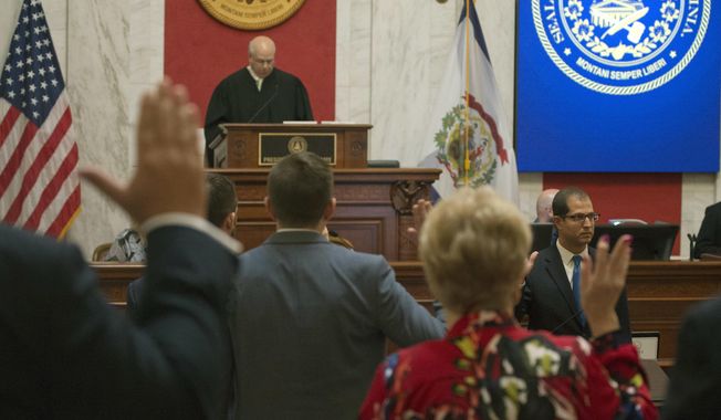 Judge Paul Farrell, left at rostrum, presides over the Senate as senators are sworn in during a pre-trial impeachment conference for four impeached Supreme Court justices in the West Virginia State Senate chambers at the Capitol in Charleston, W,Va., Tuesday, Sept. 11, 2018. Trial dates have not been set. (AP Photo/Steve Helber)