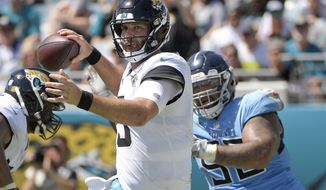 Jacksonville Jaguars quarterback Blake Bortles, left, prepares to throw a pass as he is pressured by Tennessee Titans defensive tackle DaQuan Jones, right, during the first half of an NFL football game, Sunday, Sept. 23, 2018, in Jacksonville, Fla. (AP Photo/Phelan M. Ebenhack)