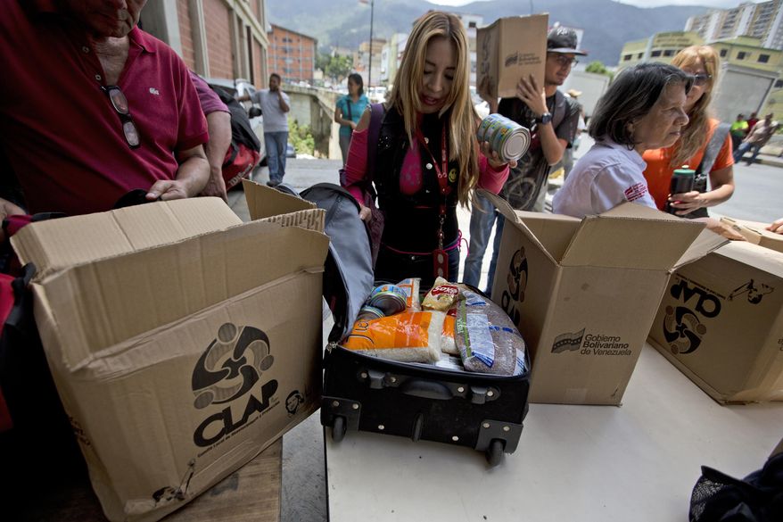 In this July 6, 2018 photo, employees of a government-supported cultural center receive boxes with subsided food distributed under a government program named &amp;quot;CLAP&amp;quot; in downtown Caracas, Venezuela. Some workers transfer the contents, cooking oil, flour, rice, canned tuna, to suitcases or backpacks for fear of becoming walking targets. (AP Photo/Fernando Llano)
