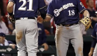 Milwaukee Brewers third baseman Mike Moustakas (18) and second baseman Travis Shaw celebrate after St. Louis Cardinals&#39; Adolis Garcia slipped rounding third and was tagged out to end the eighth inning of a baseball game Wednesday, Sept. 26, 2018, in St. Louis. (AP Photo/Jeff Roberson)