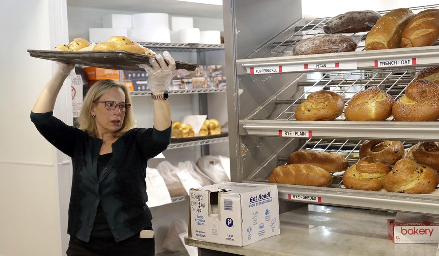 In this Sept. 18, 2018, photo Janice Jucker carries a tray of bread inside her Three Brothers Bakery in Houston. Retailers struggle in Houston a year after Hurricane Harvey flooded the city. Jucker continues to rebuild the business at Three Brothers Bakery. She has three stores, one of which was flooded; her sales are down 25 percent from before the storm. (AP Photo/David J. Phillip)