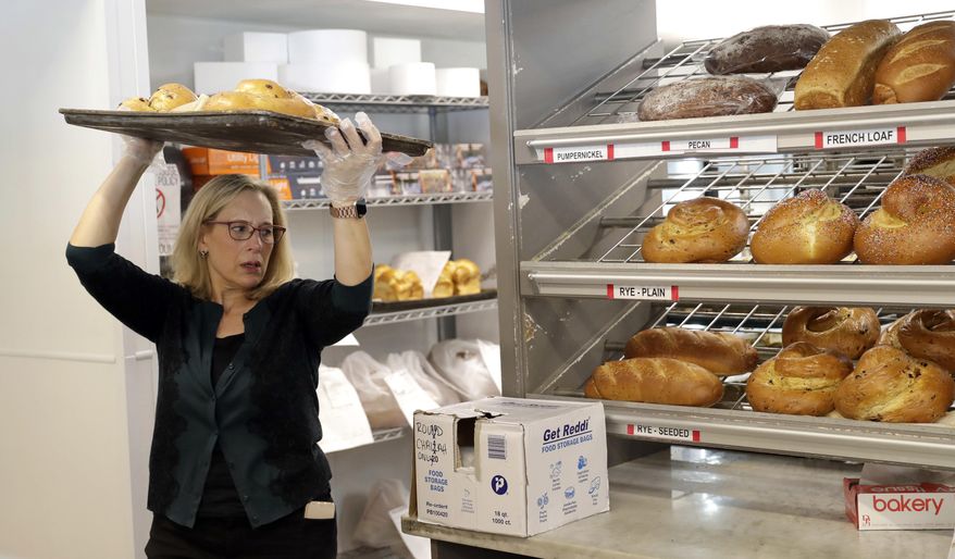 In this Sept. 18, 2018, photo Janice Jucker carries a tray of bread inside her Three Brothers Bakery in Houston. Retailers struggle in Houston a year after Hurricane Harvey flooded the city. Jucker continues to rebuild the business at Three Brothers Bakery. She has three stores, one of which was flooded; her sales are down 25 percent from before the storm. (AP Photo/David J. Phillip)